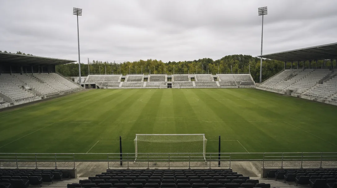 Tom läktare och gräsplan på en svensk fotbollsarena i dagsljus