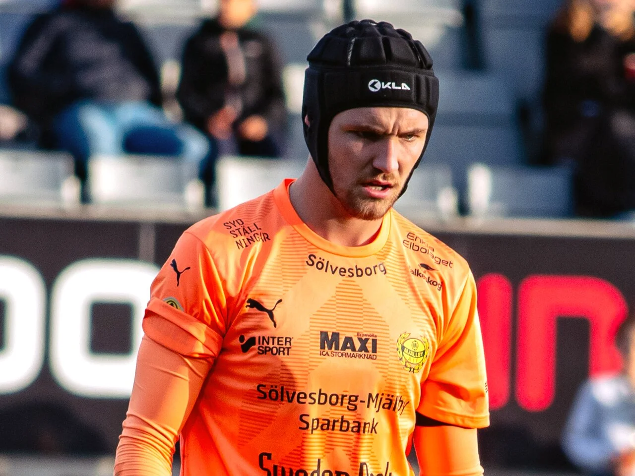 Noel Törnqvist i orange målvaktströja och svart skyddshjälm under en match för Mjällby AIF